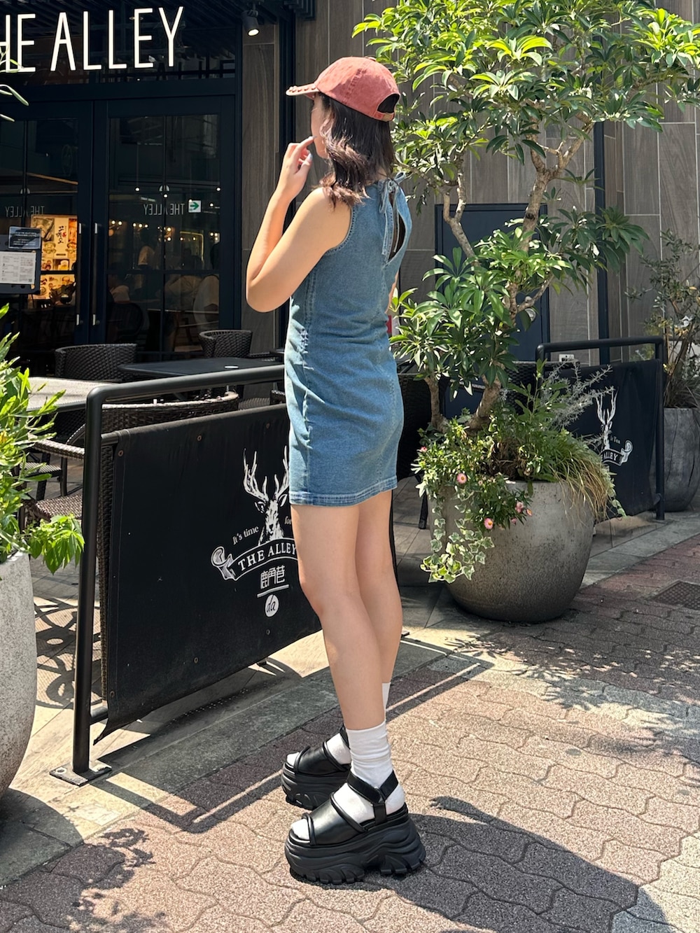 ブルー系のワンピース、ブラック系のサンダル、レッド系のキャップを着用したレディースの夏コーディネートの3枚目の写真