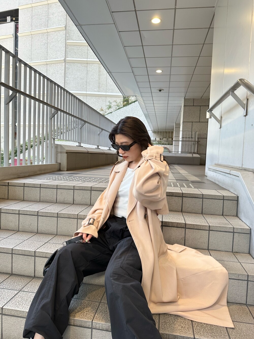 ベージュ系のトレンチコート、ブラック系のカーゴパンツ、ホワイト系のTシャツ/カットソーを着用したレディースの春コーディネートの2枚目の写真