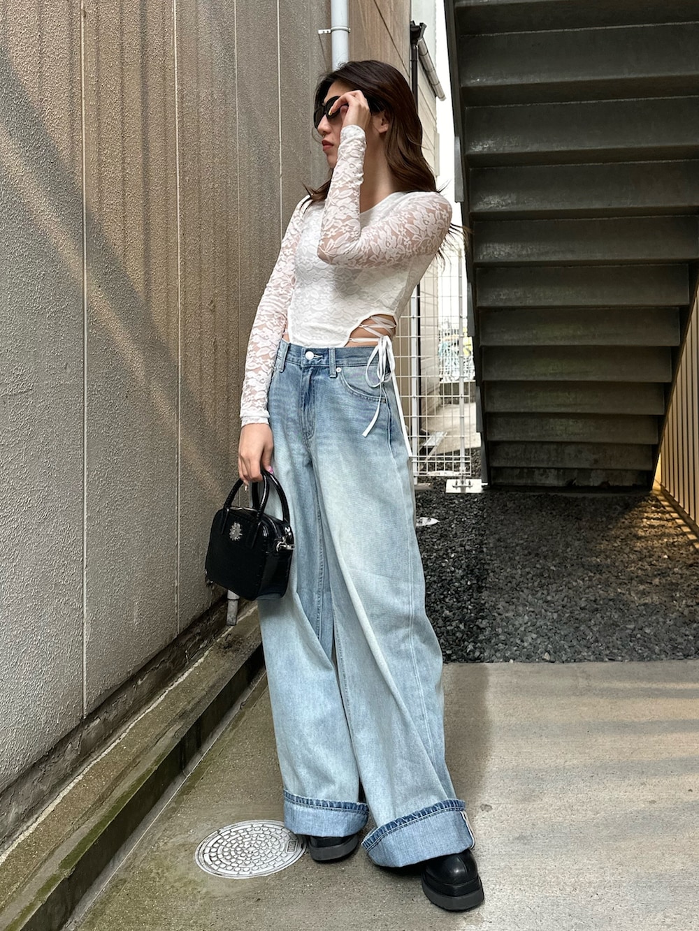 ブルー系のデニムパンツ、ホワイト系のTシャツ/カットソー、ブラック系のショルダーバッグを着用したレディースの春コーディネートの2枚目の写真