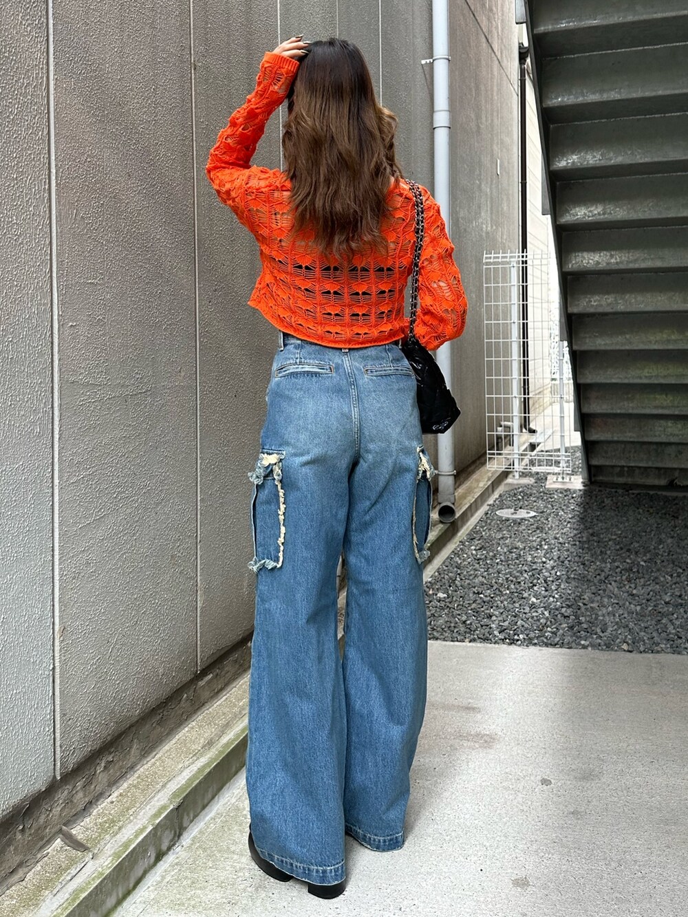 ブラック系のショルダーバッグ、ブラック系のサンダル、ブルー系のデニムパンツを着用したレディースの春コーディネートの3枚目の写真