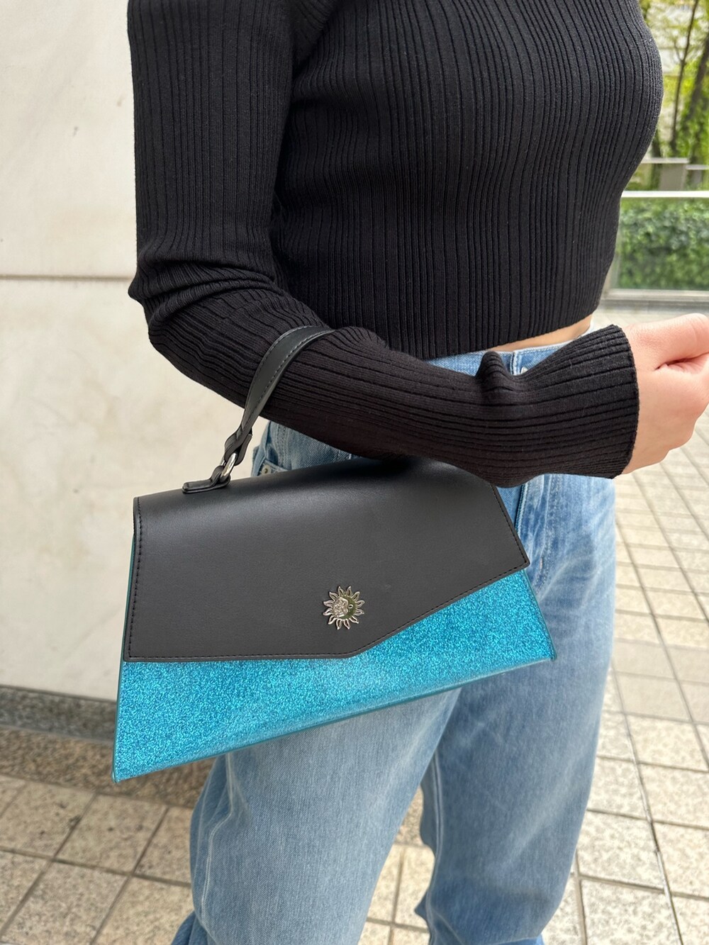 ブルー系のデニムパンツ、ブルー系のショルダーバッグ、ブラック系のニット/セーターを着用したレディースの春コーディネートの7枚目の写真