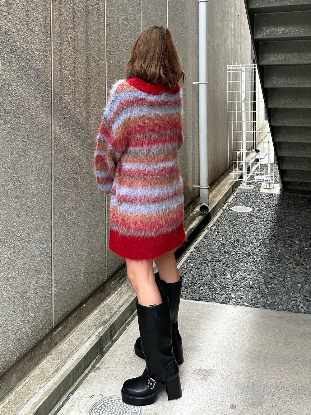 ブラウン系のブーツ、レッド系のカーディガン/ボレロ、ホワイト系のTシャツ/カットソーを着用したレディースの冬コーディネートの2枚目の写真