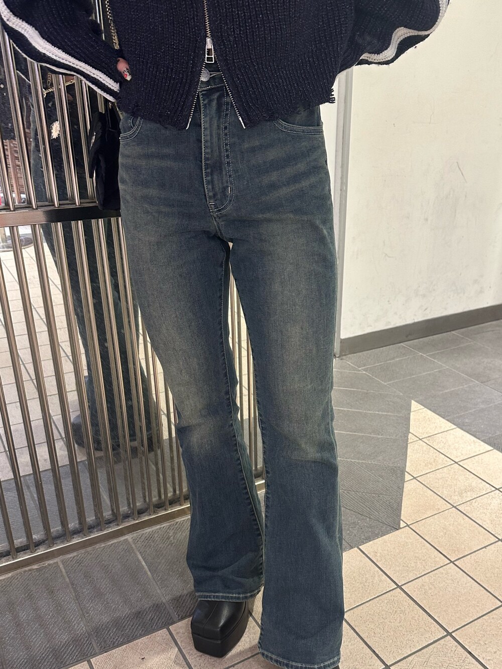 ブラック系のショルダーバッグ、ブルー系のデニムパンツ、ブラック系のブーツを着用したレディースの秋コーディネートの6枚目の写真