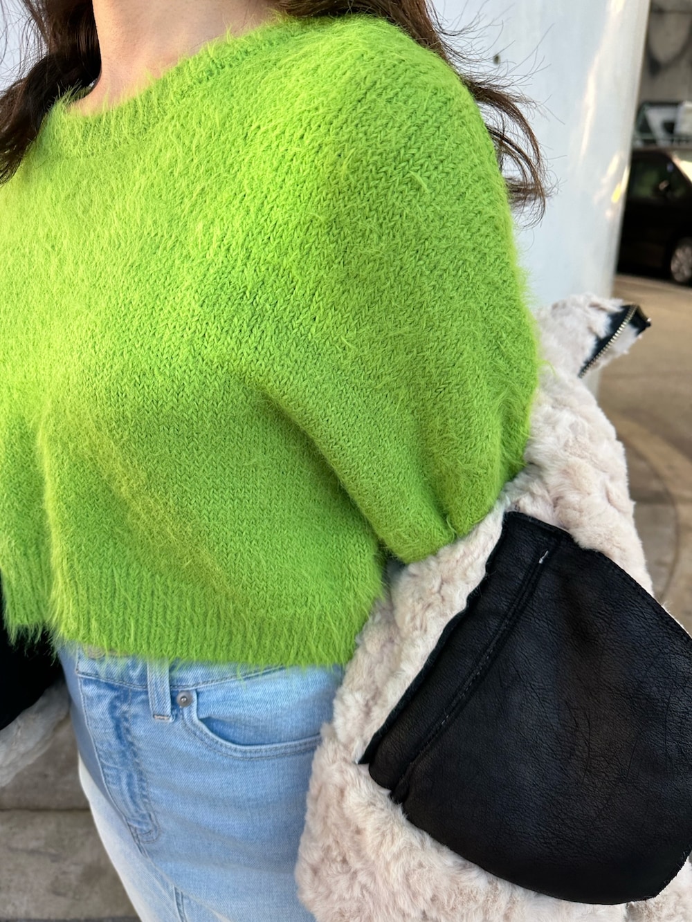 ブルー系のデニムスカート、グリーン系のニット/セーター、ブラック系のムートンコートを着用したレディースの冬コーディネートの5枚目の写真