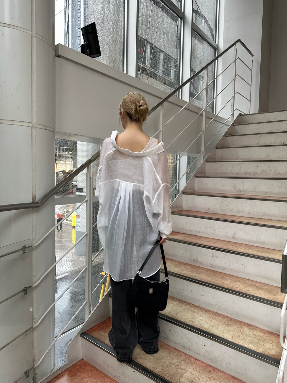 ブラック系のサンダル、ブラック系のハンドバッグ、ブラック系のデニムパンツを着用したレディースの夏コーディネートの3枚目の写真