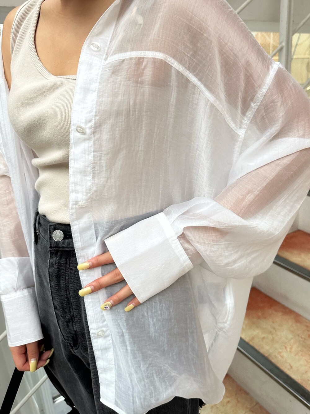 ブラック系のサンダル、ブラック系のハンドバッグ、ブラック系のデニムパンツを着用したレディースの夏コーディネートの6枚目の写真