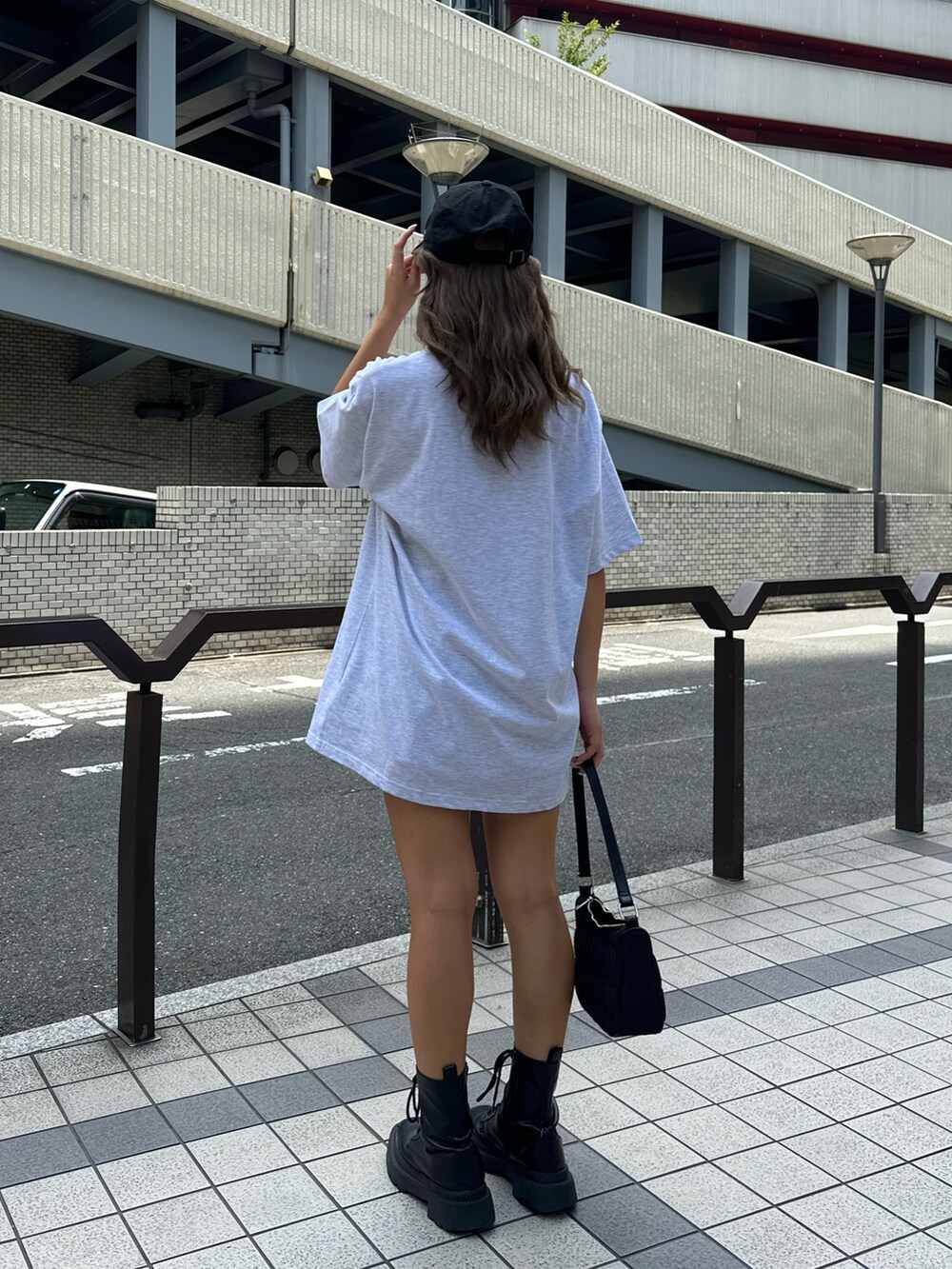 グレー系のTシャツ/カットソー、ブラック系のハンドバッグ、ブラック系のブーツを着用したレディースの夏コーディネートの3枚目の写真