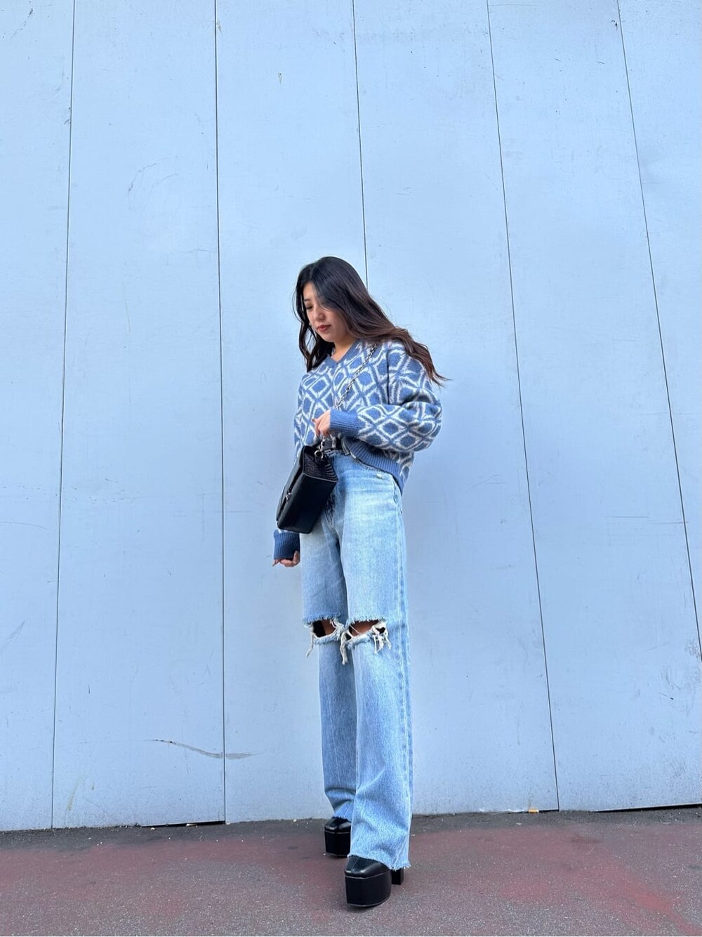ブラック系のブーツ、ブルー系のニット/セーター、ブルー系のデニムパンツを着用したレディースの秋コーディネートの2枚目の写真