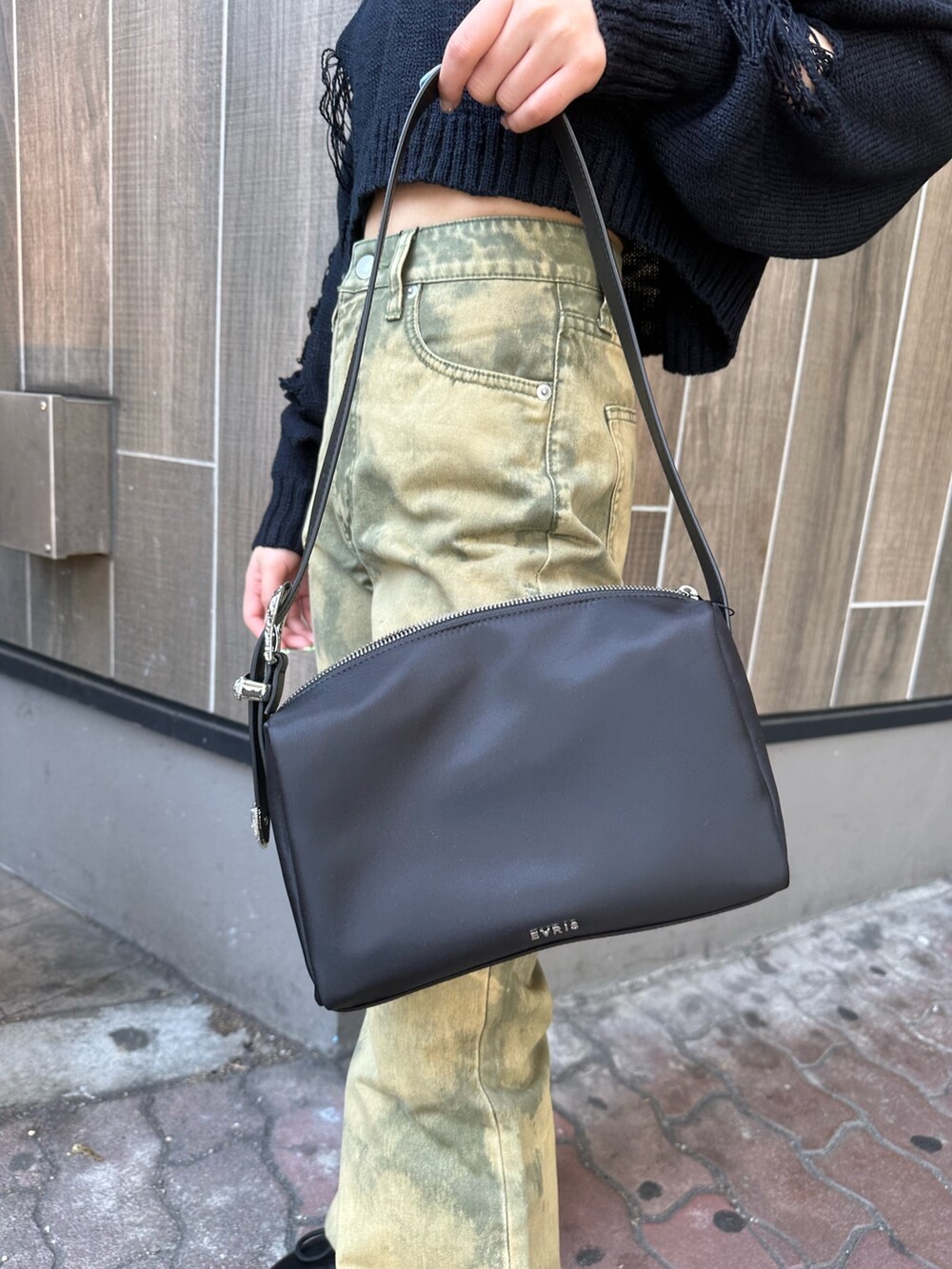 ブラック系のニット/セーター、ブラック系のハンドバッグ、イエロー系のデニムパンツを着用したレディースの春コーディネートの6枚目の写真