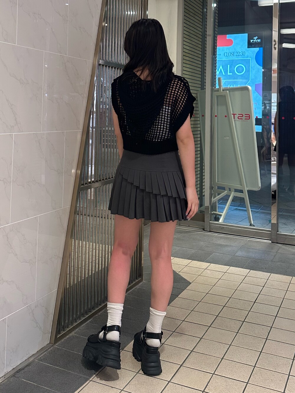 ブラック系のニット/セーター、グレー系のスカート、ブラック系のサンダルを着用したレディースの夏コーディネートの3枚目の写真