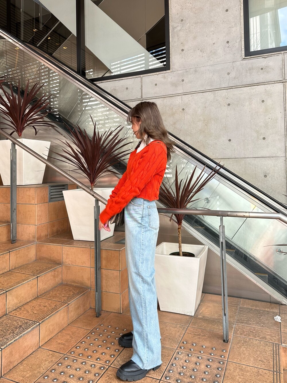 オレンジ系のカーディガン/ボレロ、ホワイト系のシャツ/ブラウス、ブルー系のデニムパンツを着用したレディースの冬コーディネートの2枚目の写真