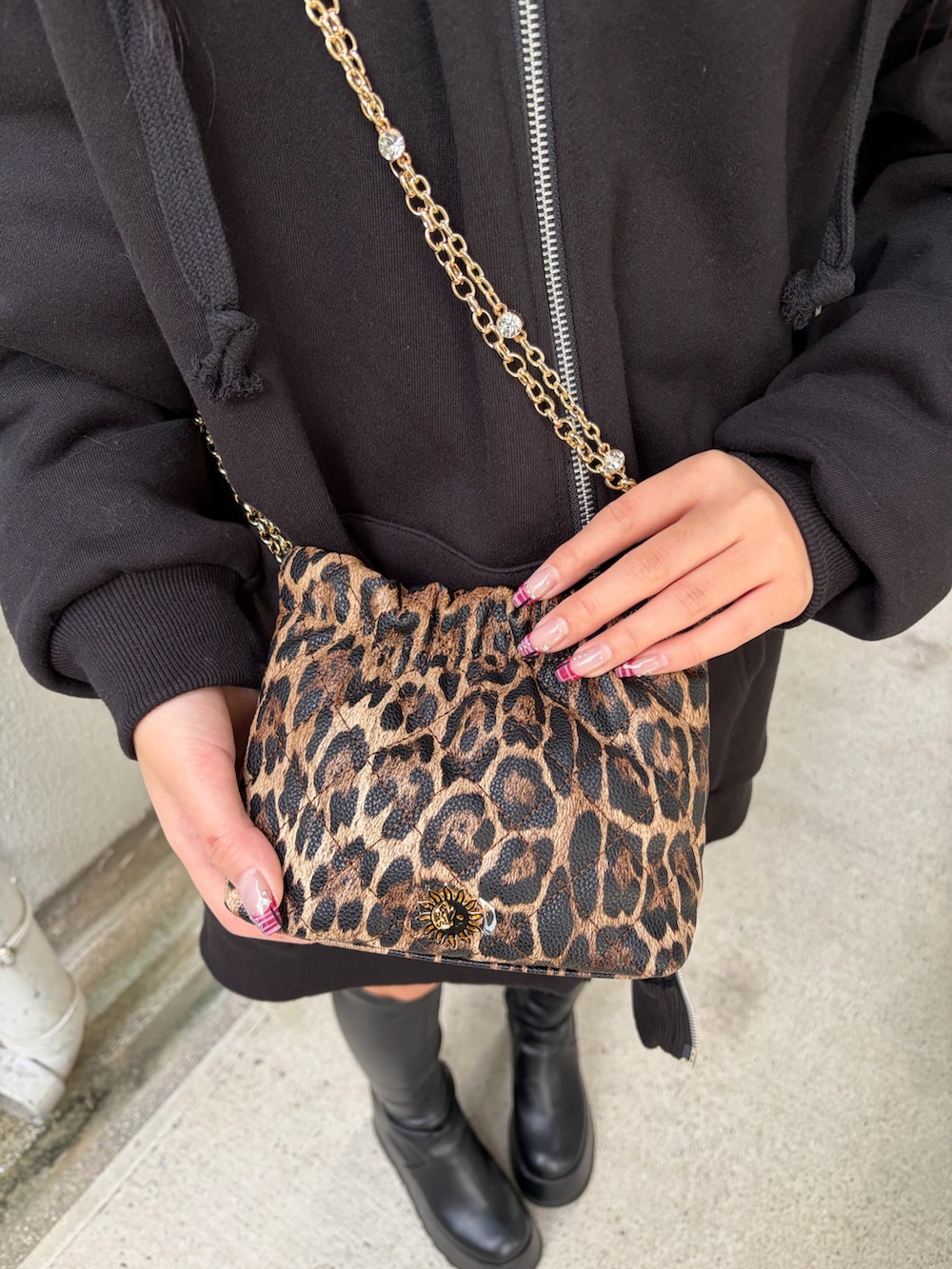 ブラック系のパーカー、ブラック系のブーツ、ブラック系のショルダーバッグを着用したレディースの秋コーディネートの6枚目の写真