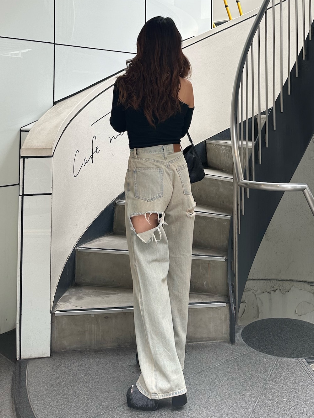 ブルー系のデニムパンツ、ブラック系のサンダル、ブラック系のTシャツ/カットソーを着用したレディースの秋コーディネートの2枚目の写真