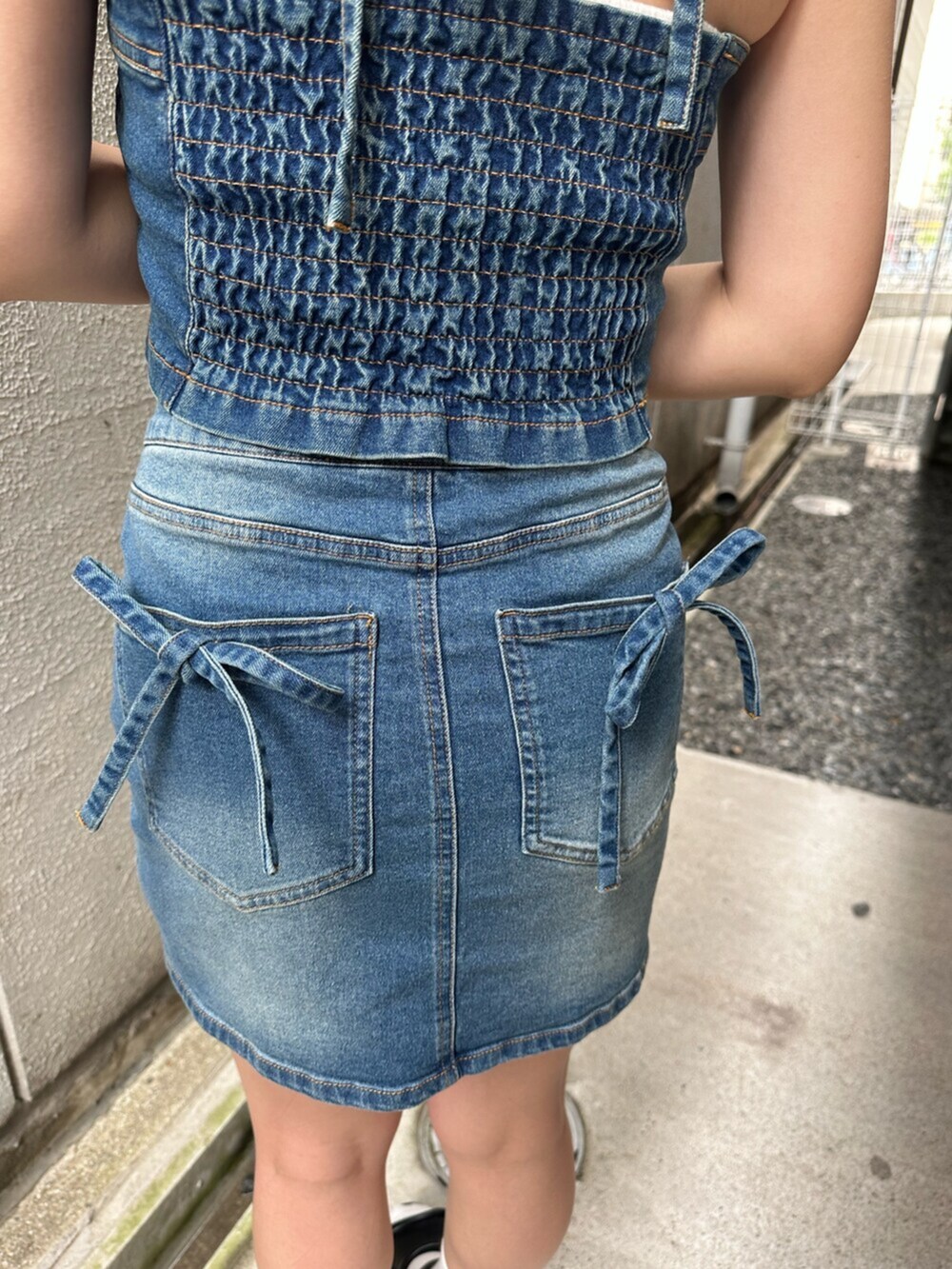 ブラック系のサンダル、ブルー系のキャミソール、ブルー系のデニムスカートを着用したレディースの夏コーディネートの6枚目の写真