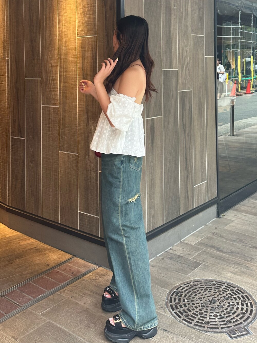 ブルー系のデニムパンツ、ホワイト系のシャツ/ブラウス、レッド系のショルダーバッグを着用したレディースの夏コーディネートの3枚目の写真