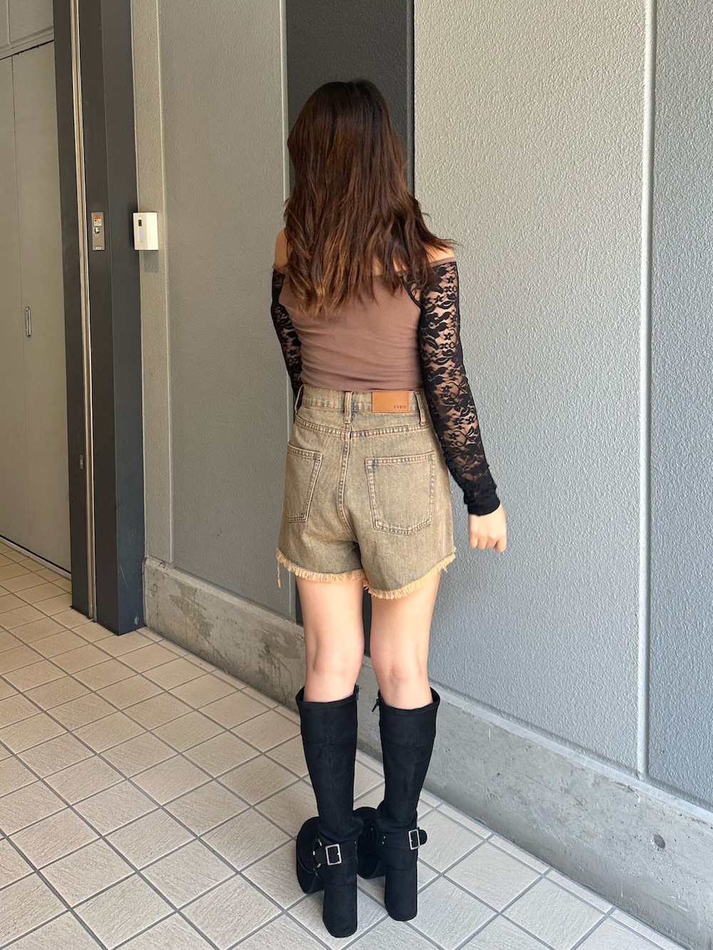 ブルー系のデニムパンツ、ブラック系のブーツ、ブラウン系のTシャツ/カットソーを着用したレディースの秋コーディネートの3枚目の写真