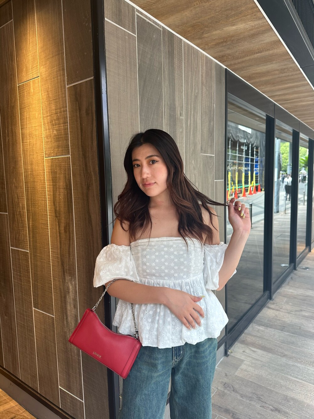 ブルー系のデニムパンツ、ホワイト系のシャツ/ブラウス、レッド系のショルダーバッグを着用したレディースの夏コーディネートの6枚目の写真