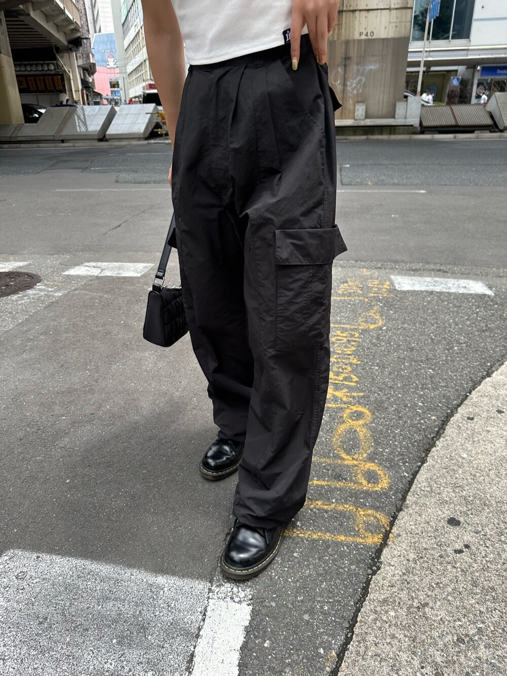 ブラック系のカーゴパンツ、ホワイト系のTシャツ/カットソー、ブラック系のハンドバッグを着用したレディースの夏コーディネートの6枚目の写真