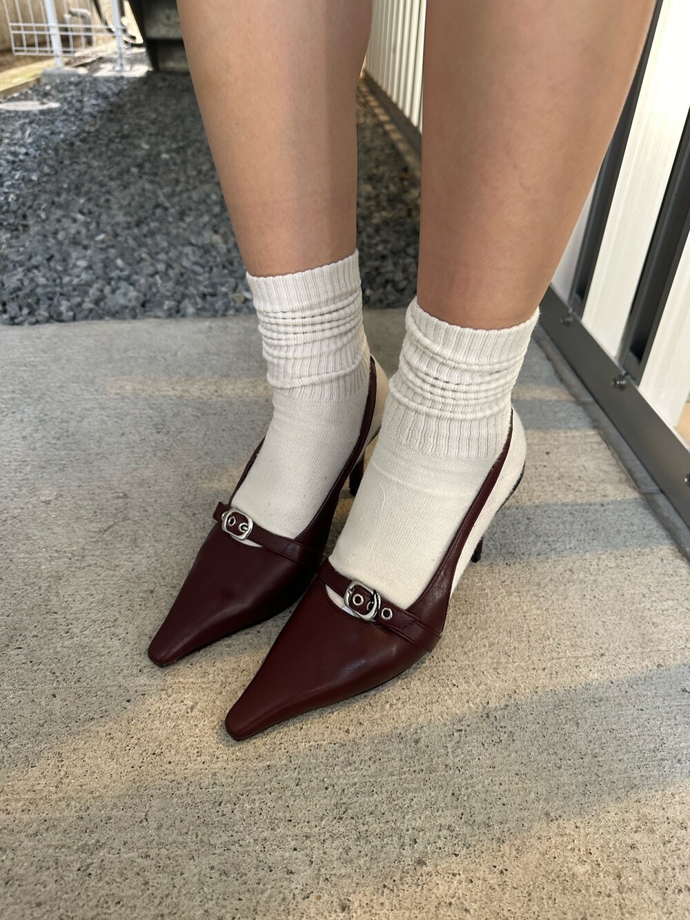 グレー系のワンピース、ブラック系のテーラードジャケット、レッド系のパンプスを着用したレディースの秋コーディネートの8枚目の写真