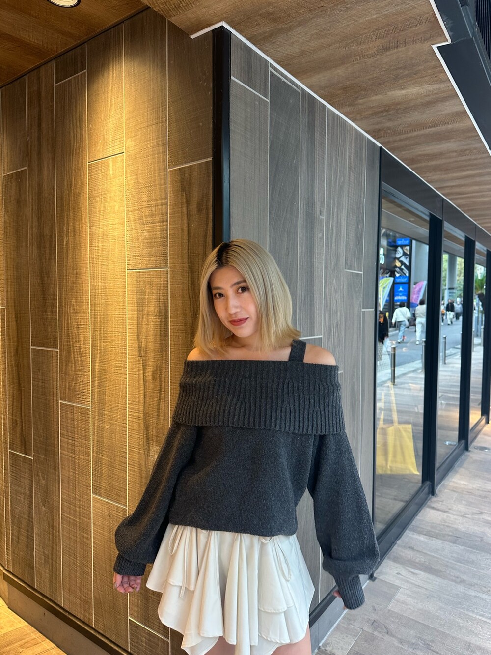 グレー系のワンピース、ホワイト系のスカート、ブラック系のブーツを着用したレディースの秋コーディネートの5枚目の写真