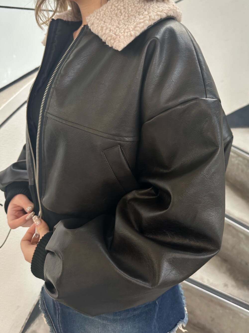 ブルー系のデニムスカート、ブラック系のブーツ、ブラック系のブルゾンを着用したレディースの冬コーディネートの5枚目の写真