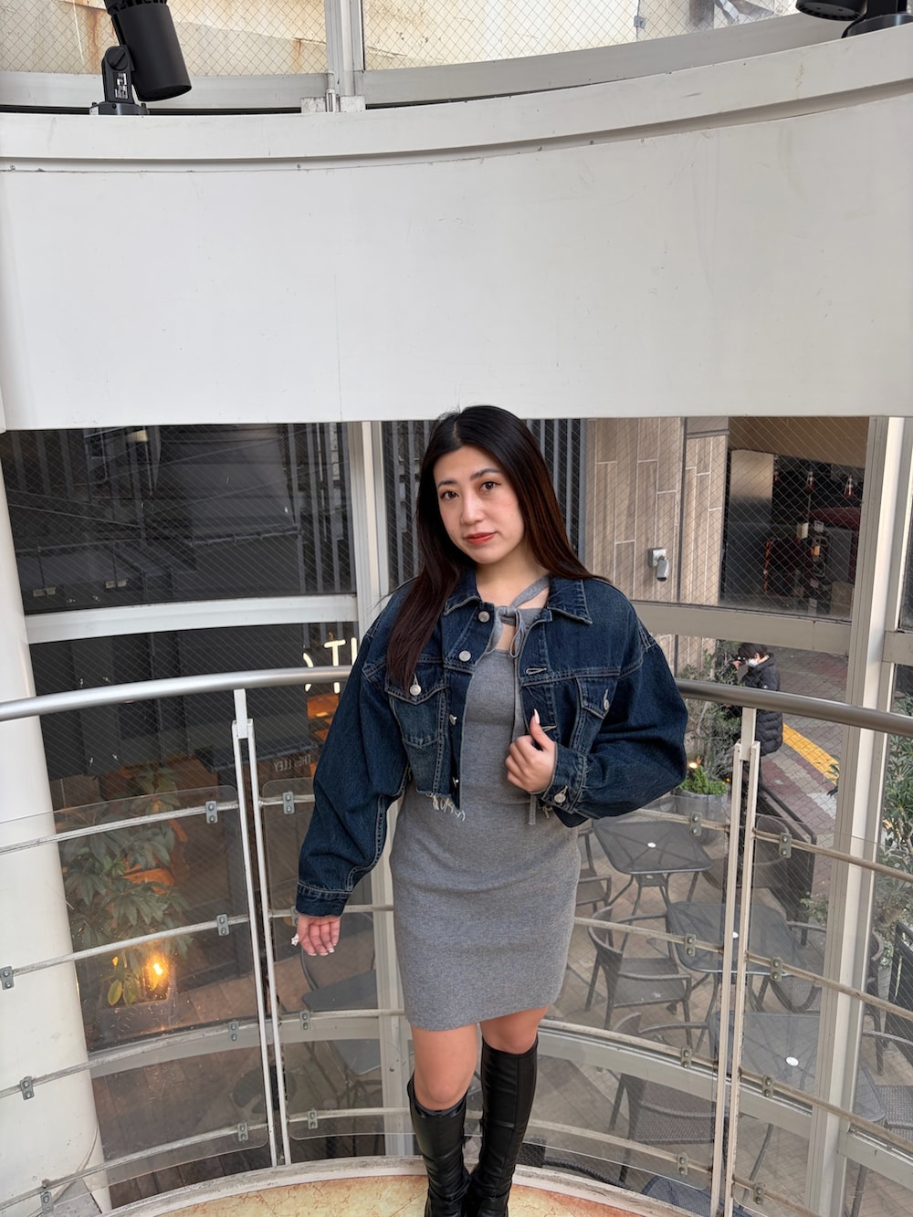 ブラック系のブーツ、ブルー系のデニムジャケット、グレー系のワンピースを着用したレディースの冬コーディネートの4枚目の写真