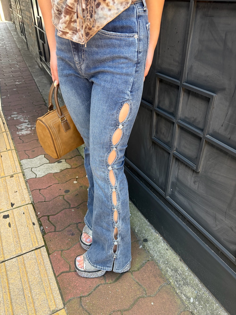 ブルー系のデニムパンツ、ブラウン系のボストンバッグ、ベージュ系のキャミソールを着用したレディースの夏コーディネートの7枚目の写真