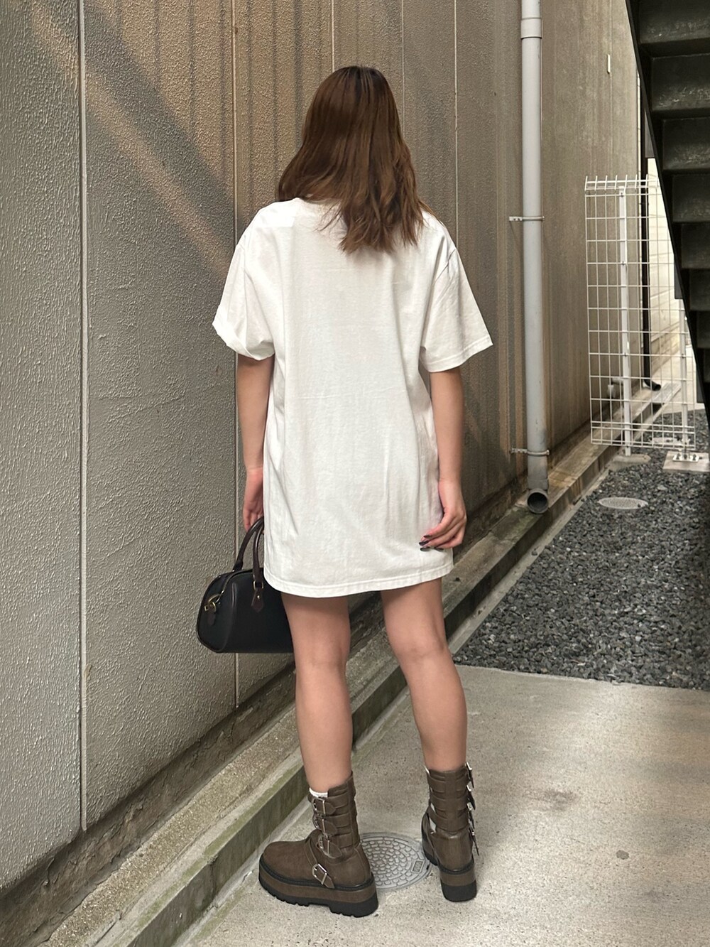 ホワイト系のTシャツ/カットソー、ブラック系のショルダーバッグ、ブラウン系のブーツを着用したレディースの夏コーディネートの3枚目の写真
