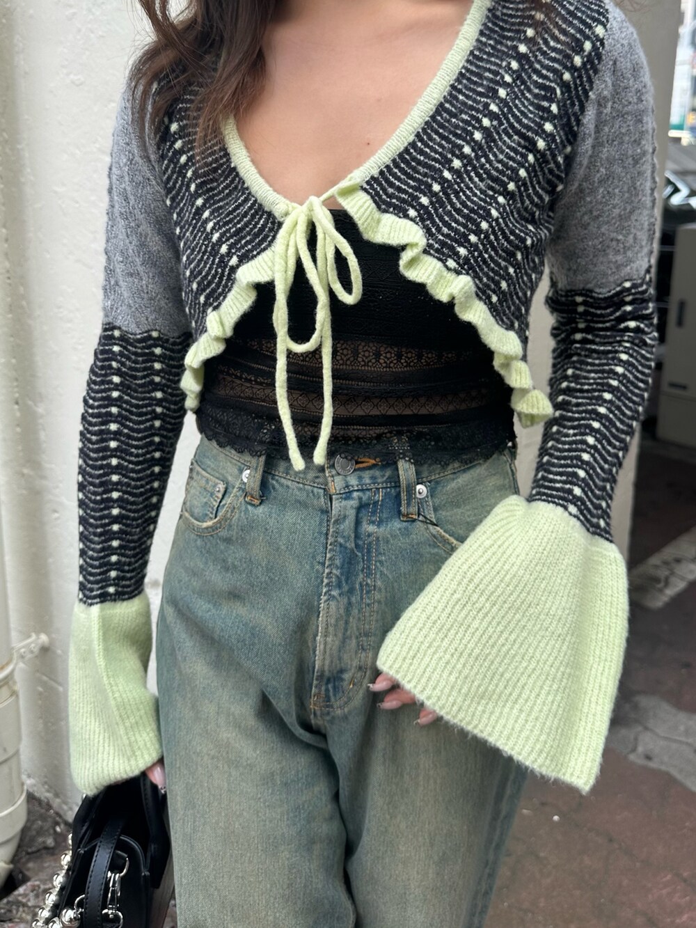 イエロー系のニット/セーター、ブルー系のデニムパンツ、ブラック系のショルダーバッグを着用したレディースの秋コーディネートの5枚目の写真