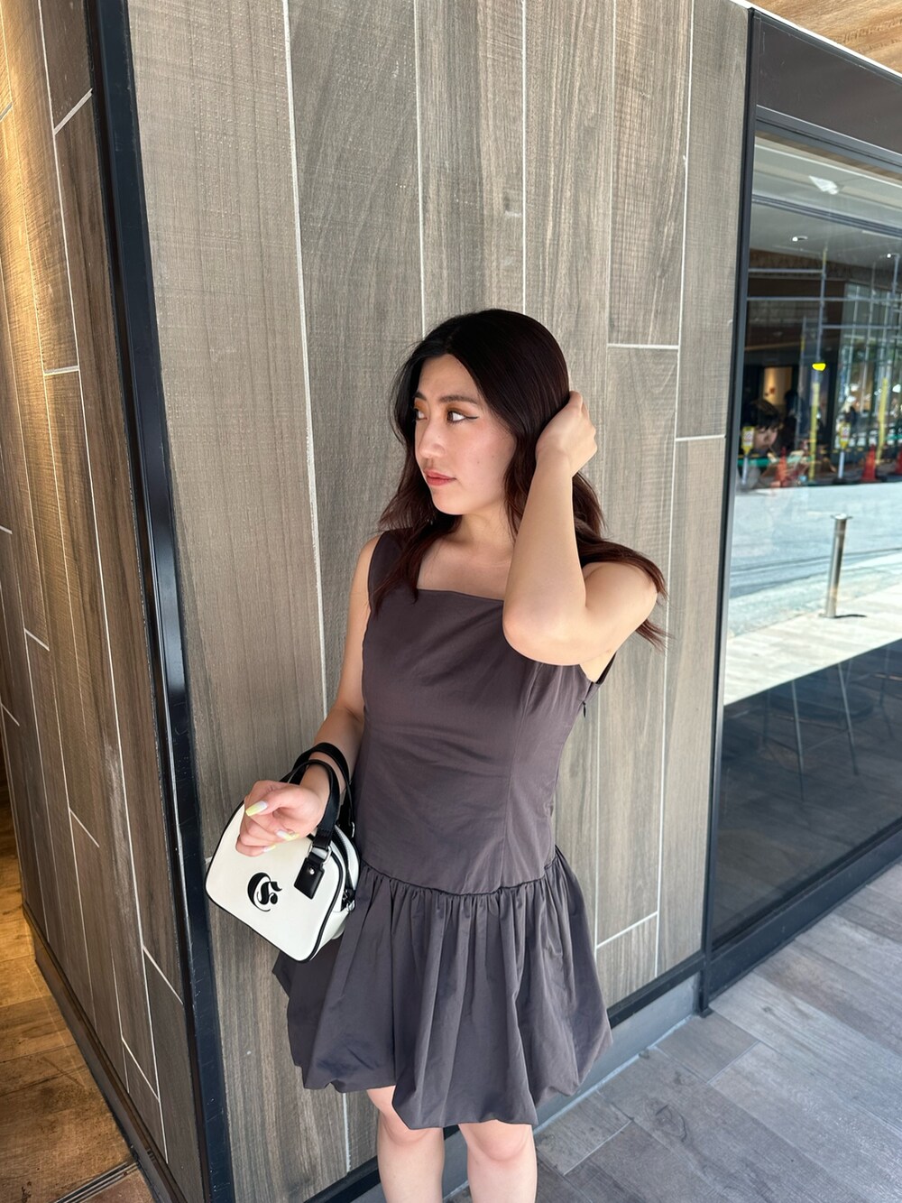 グレー系のワンピース、ホワイト系のショルダーバッグ、ブラック系のブーツを着用したレディースの夏コーディネートの5枚目の写真