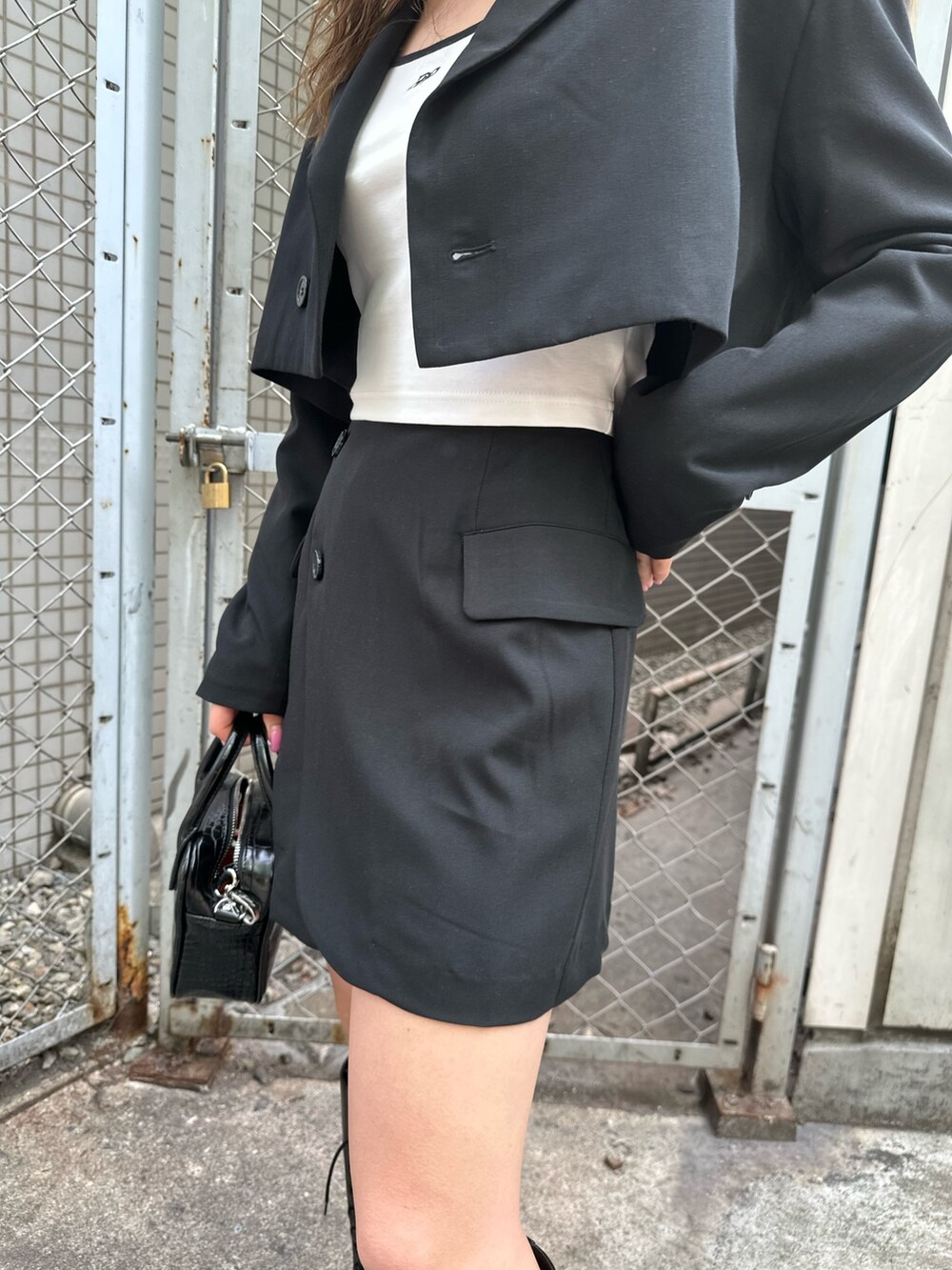 ホワイト系のTシャツ/カットソー、ブラック系のテーラードジャケット、ブラック系のスカートを着用したレディースの春コーディネートの6枚目の写真