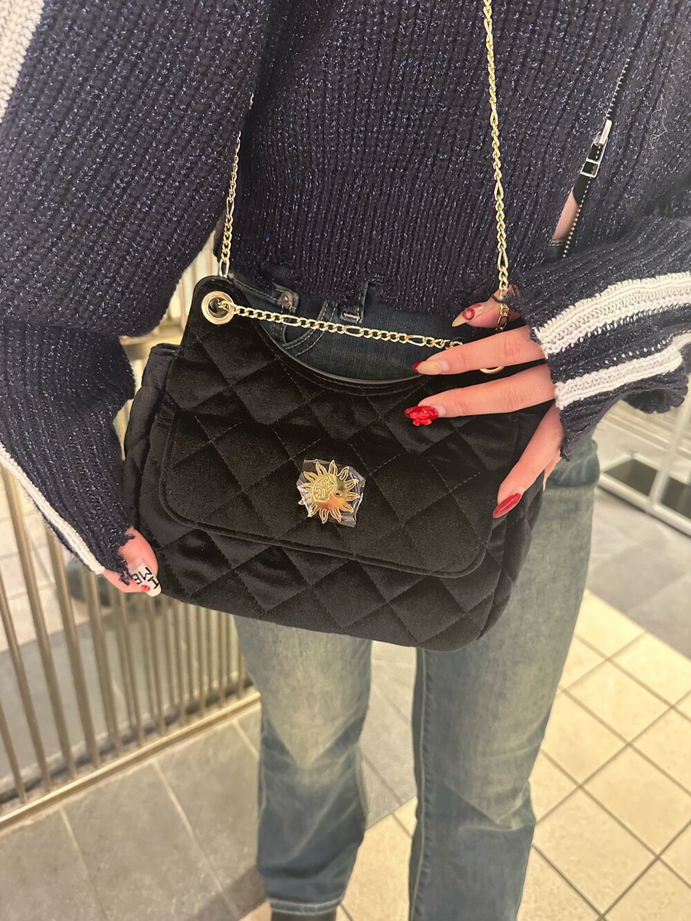 ブラック系のショルダーバッグ、ブルー系のデニムパンツ、ブラック系のブーツを着用したレディースの秋コーディネートの7枚目の写真
