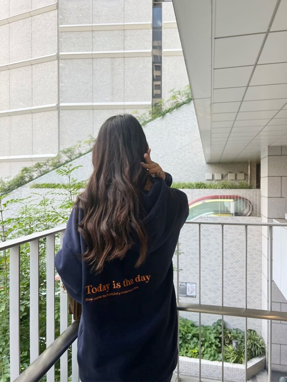 ブラック系のブーツ、ブラウン系のハンドバッグ、ブルー系のパーカーを着用したレディースの秋コーディネートの5枚目の写真