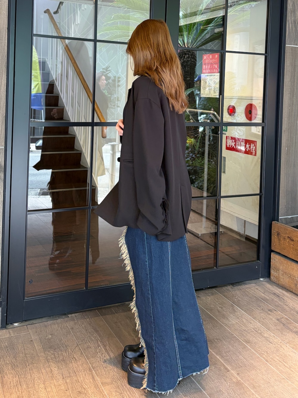 ブルー系のワンピース、ブラック系のブーツ、ブラック系のテーラードジャケットを着用したレディースの春コーディネートの2枚目の写真