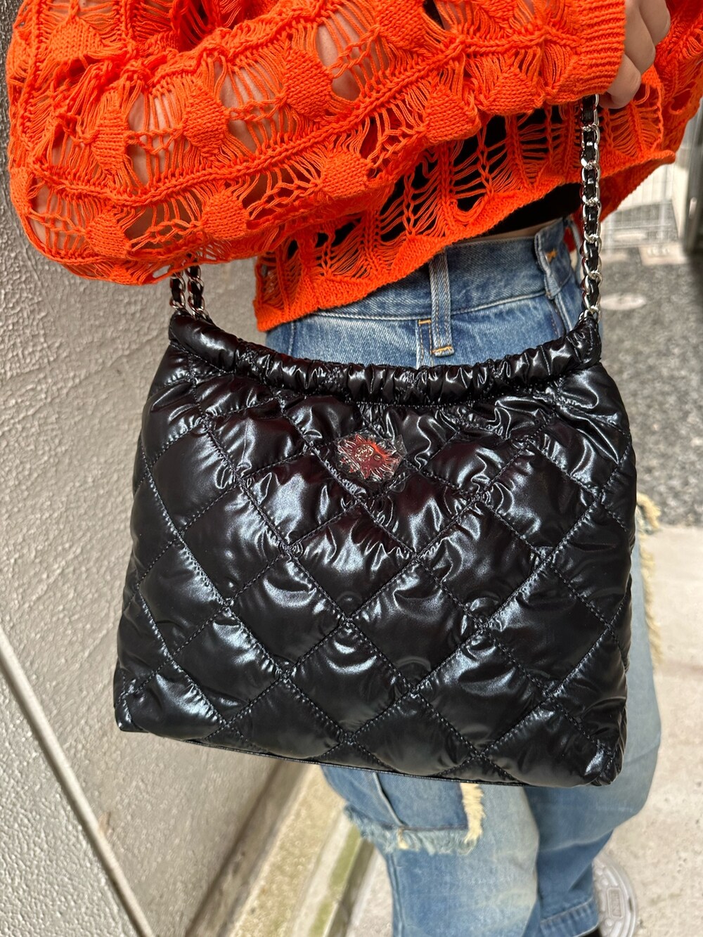 ブラック系のショルダーバッグ、ブラック系のサンダル、ブルー系のデニムパンツを着用したレディースの春コーディネートの6枚目の写真