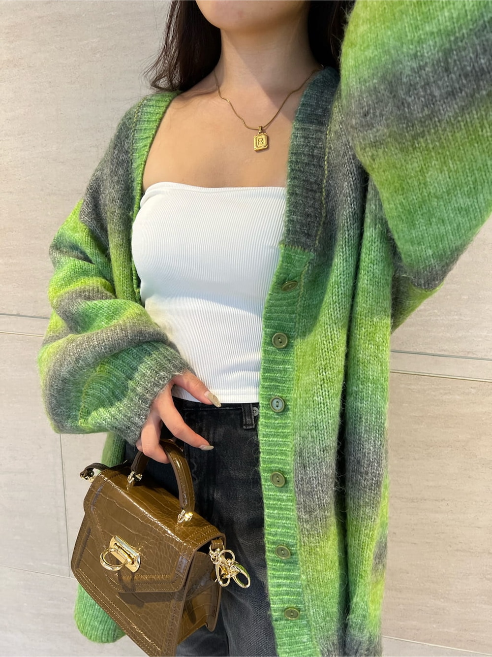 グリーン系のカーディガン/ボレロ、ホワイト系のチューブトップ、ブラック系のデニムパンツを着用したレディースの秋コーディネートの3枚目の写真