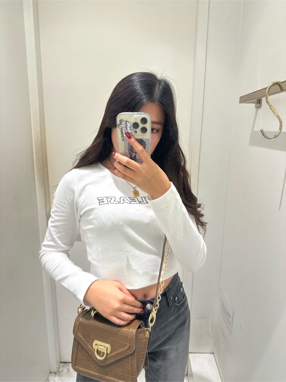 ブラック系のMA-1、ブラウン系のハンドバッグ、ブラック系のデニムパンツを着用したレディースの秋コーディネートの4枚目の写真