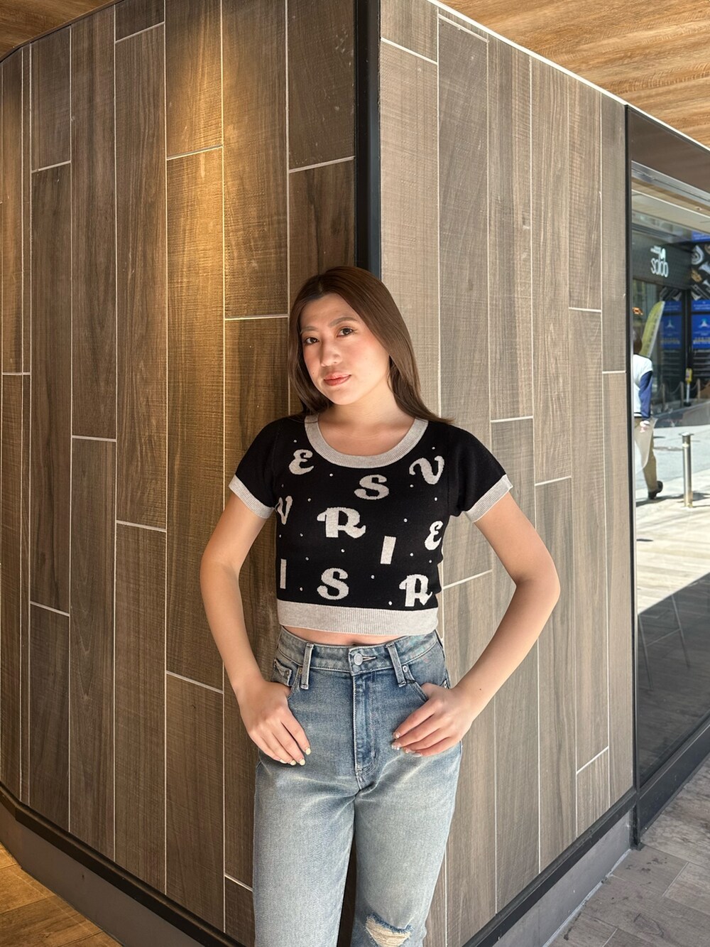 ブラック系のニット/セーター、ブルー系のデニムパンツ、その他のサンダルを着用したレディースの春コーディネートの5枚目の写真