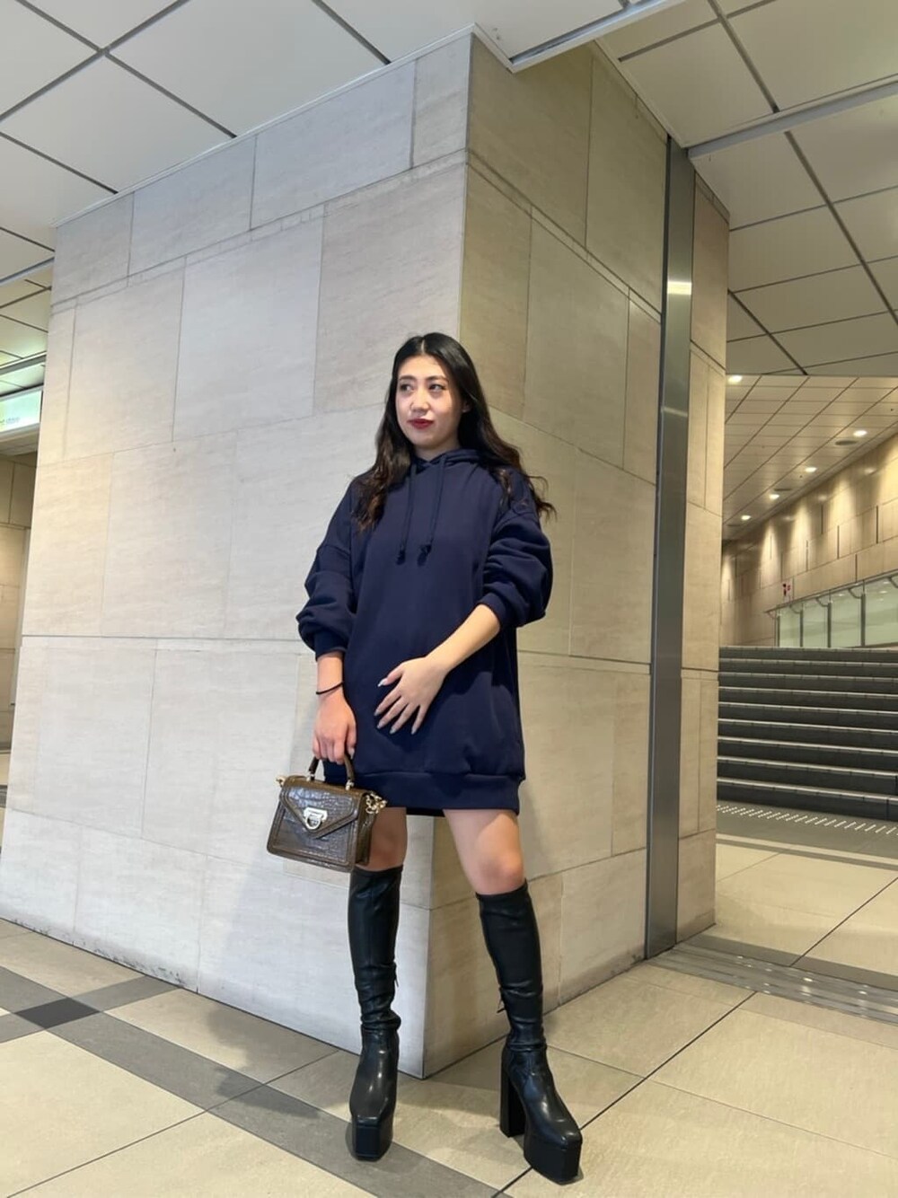 ブラック系のブーツ、ブラウン系のハンドバッグ、ブルー系のパーカーを着用したレディースの秋コーディネートの3枚目の写真