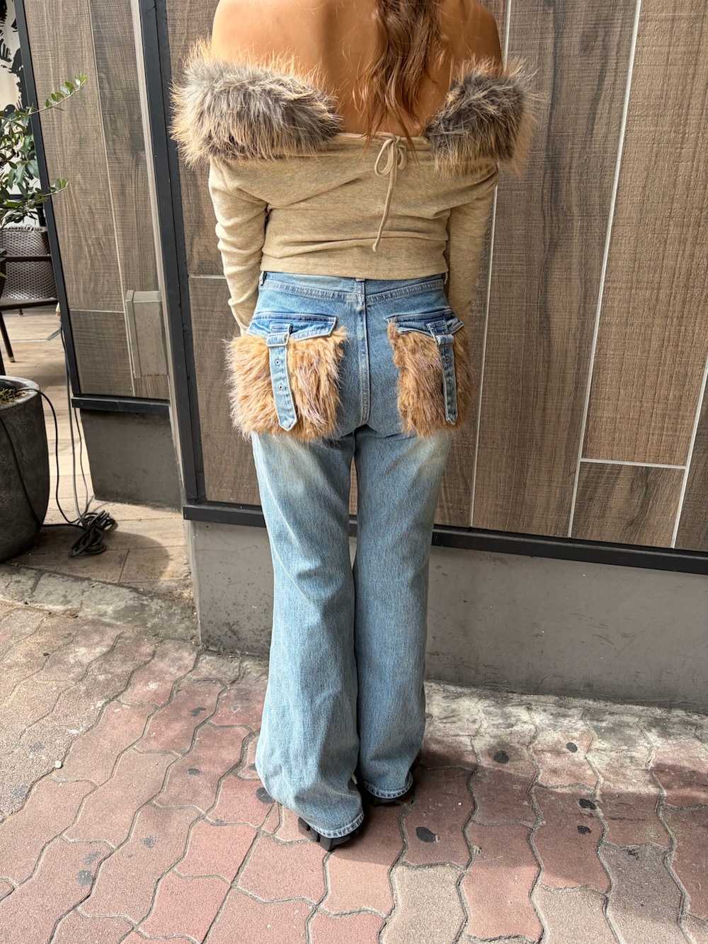 ブルー系のデニムパンツ、ベージュ系のTシャツ/カットソー、ブラック系のブーツを着用したレディースの秋コーディネートの6枚目の写真