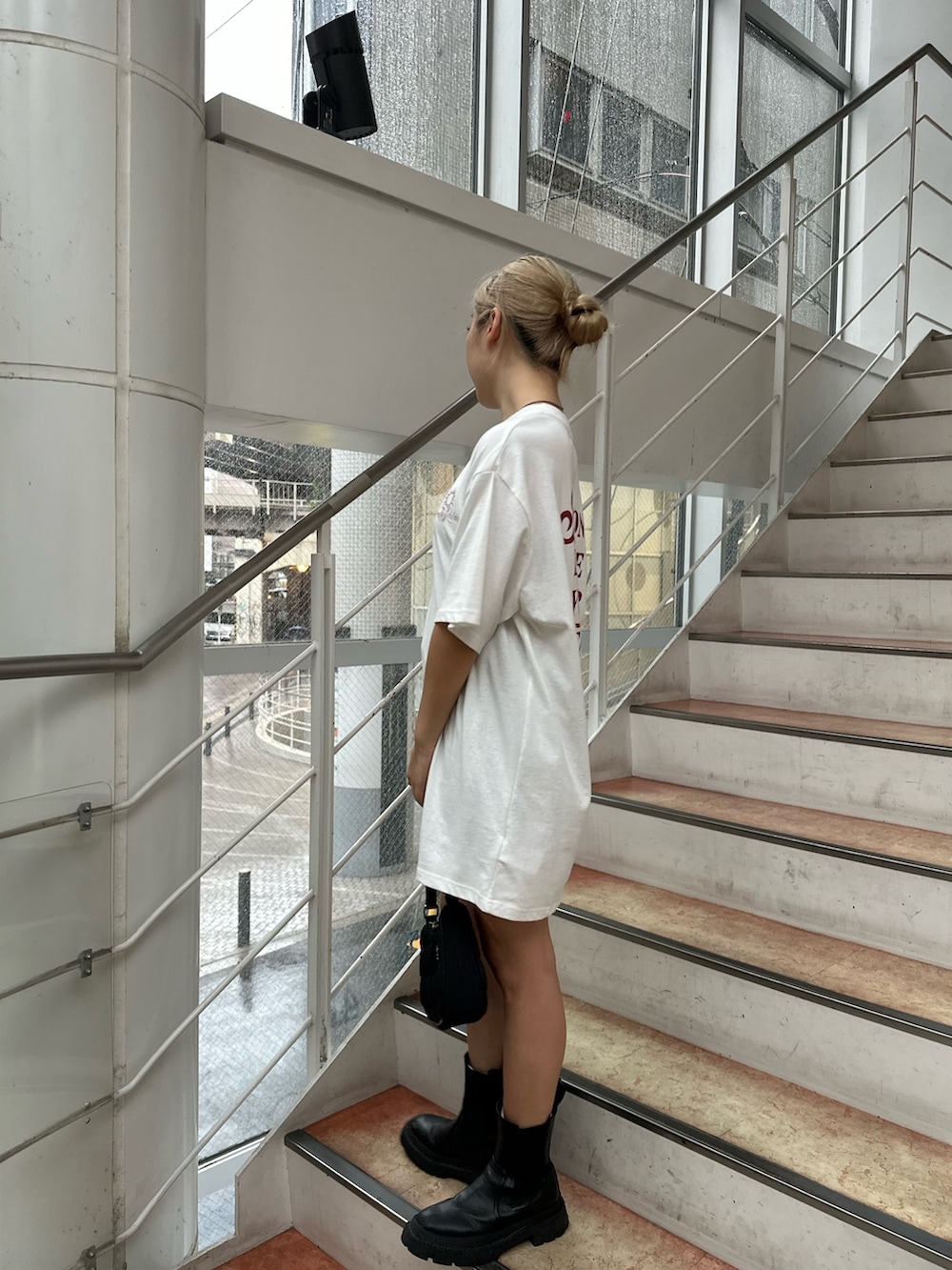 ホワイト系のTシャツ/カットソー、ブラック系のブーツ、ブラック系のハンドバッグを着用したレディースの夏コーディネートの2枚目の写真