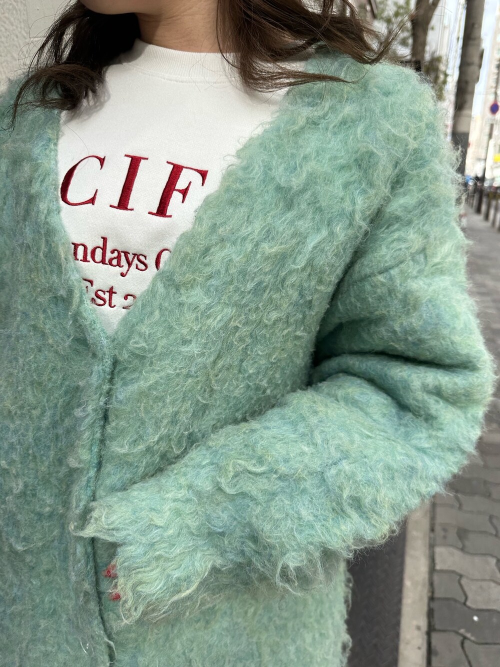 ホワイト系のショルダーバッグ、グリーン系のカーディガン/ボレロ、ブラック系のブーツを着用したレディースの冬コーディネートの4枚目の写真