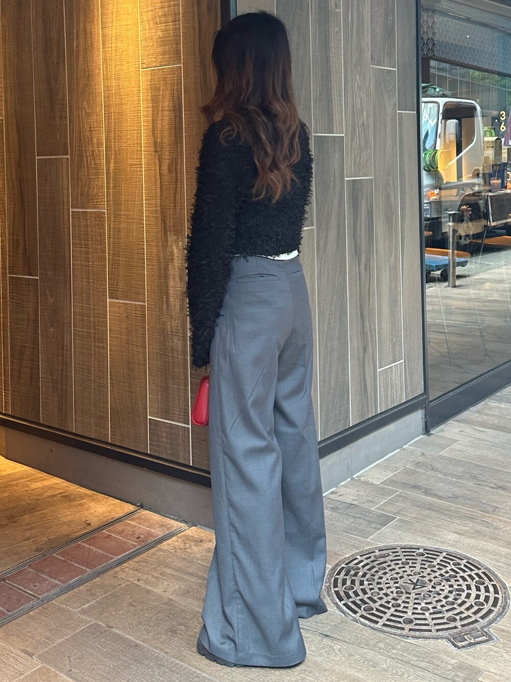 ブラック系のニット/セーター、グレー系のその他パンツ、レッド系のショルダーバッグを着用したレディースの秋コーディネートの2枚目の写真