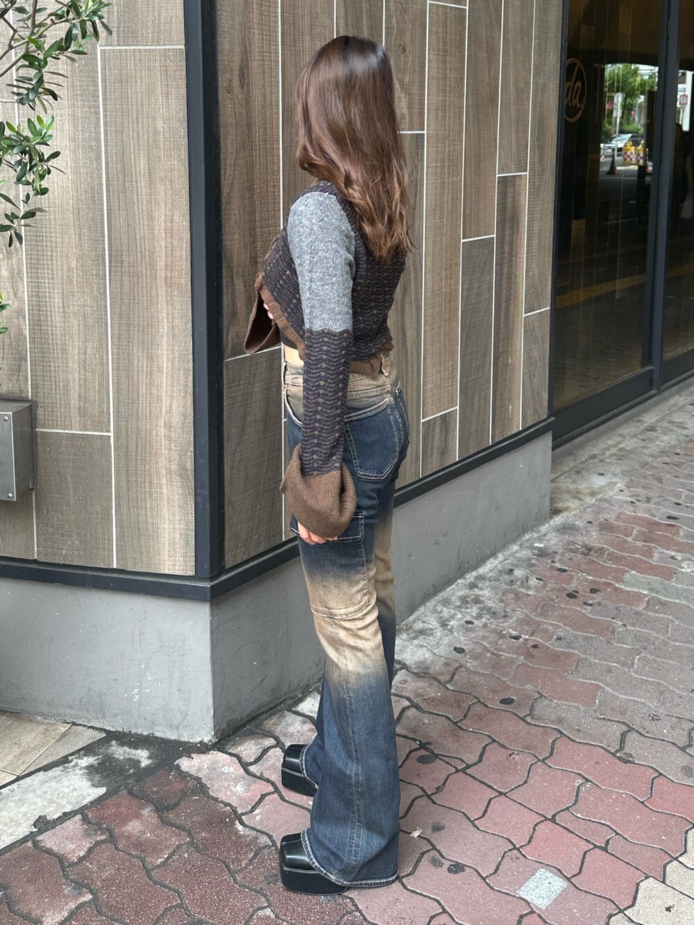 ブルー系のデニムパンツ、ブラック系のブーツ、ブラウン系のニット/セーターを着用したレディースの秋コーディネートの2枚目の写真