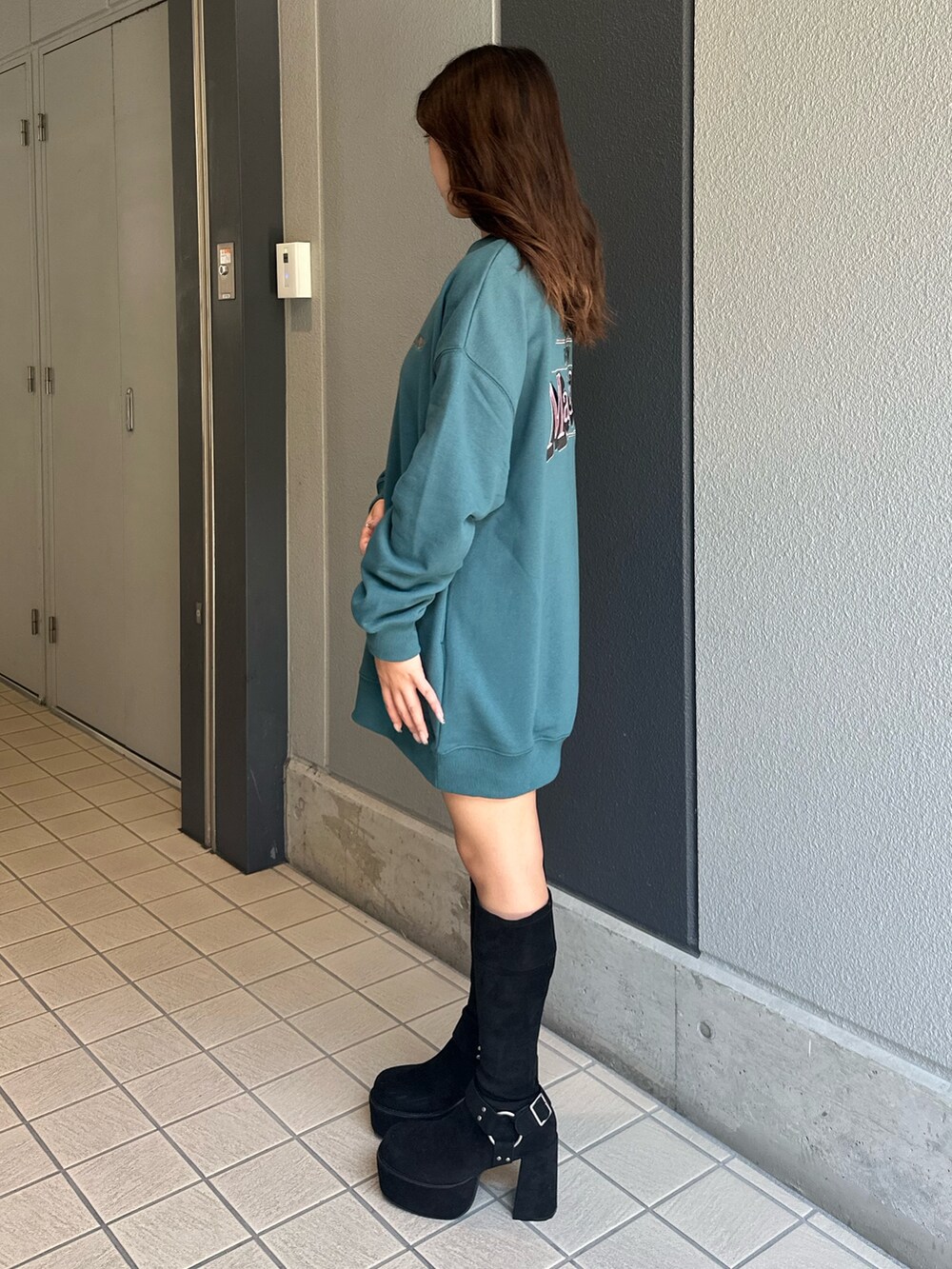 ブルー系のスウェット、ブラック系のブーツ、ブルー系のデニムパンツを着用したレディースの秋コーディネートの2枚目の写真