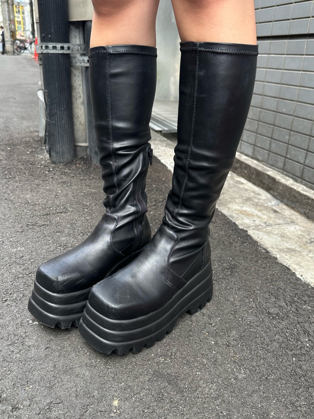 ブラック系のブーツ、ベージュ系のニット/セーター、ブラック系のデニムスカートを着用したレディースの冬コーディネートの7枚目の写真