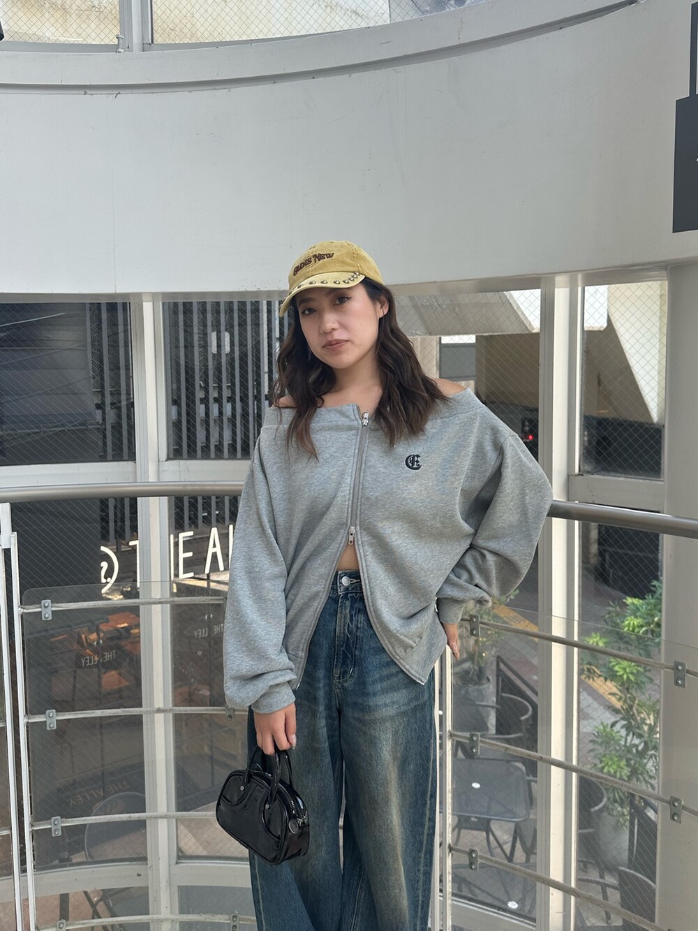 ブルー系のデニムパンツ、グレー系のパーカー、ブラック系のハンドバッグを着用したレディースの秋コーディネートの5枚目の写真