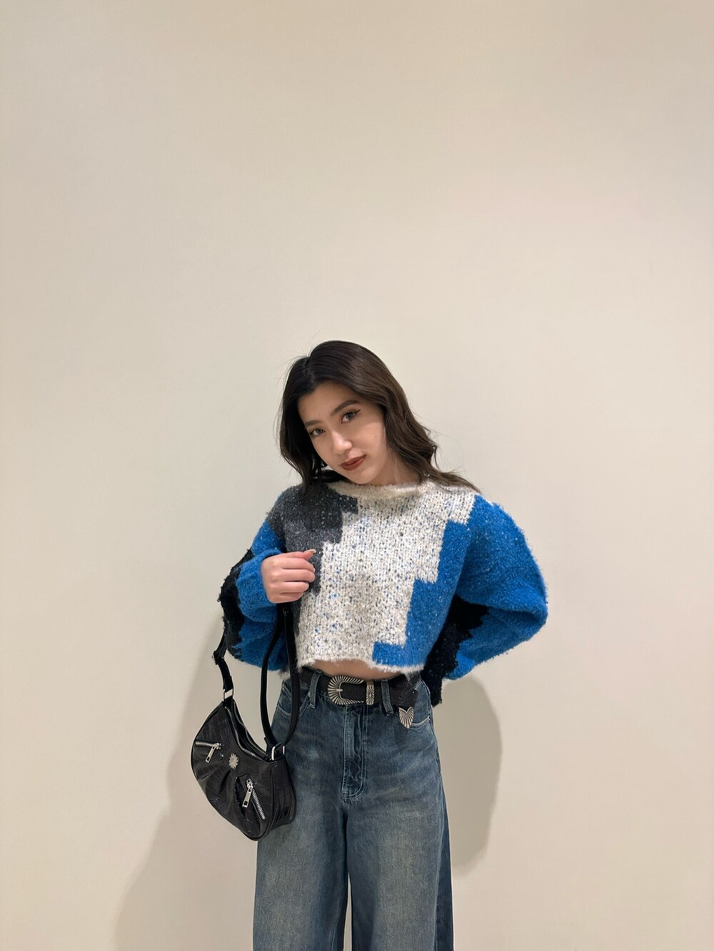 ブルー系のデニムパンツ、ブラック系のショルダーバッグ、ブラック系のブーツを着用したレディースの冬コーディネートの4枚目の写真