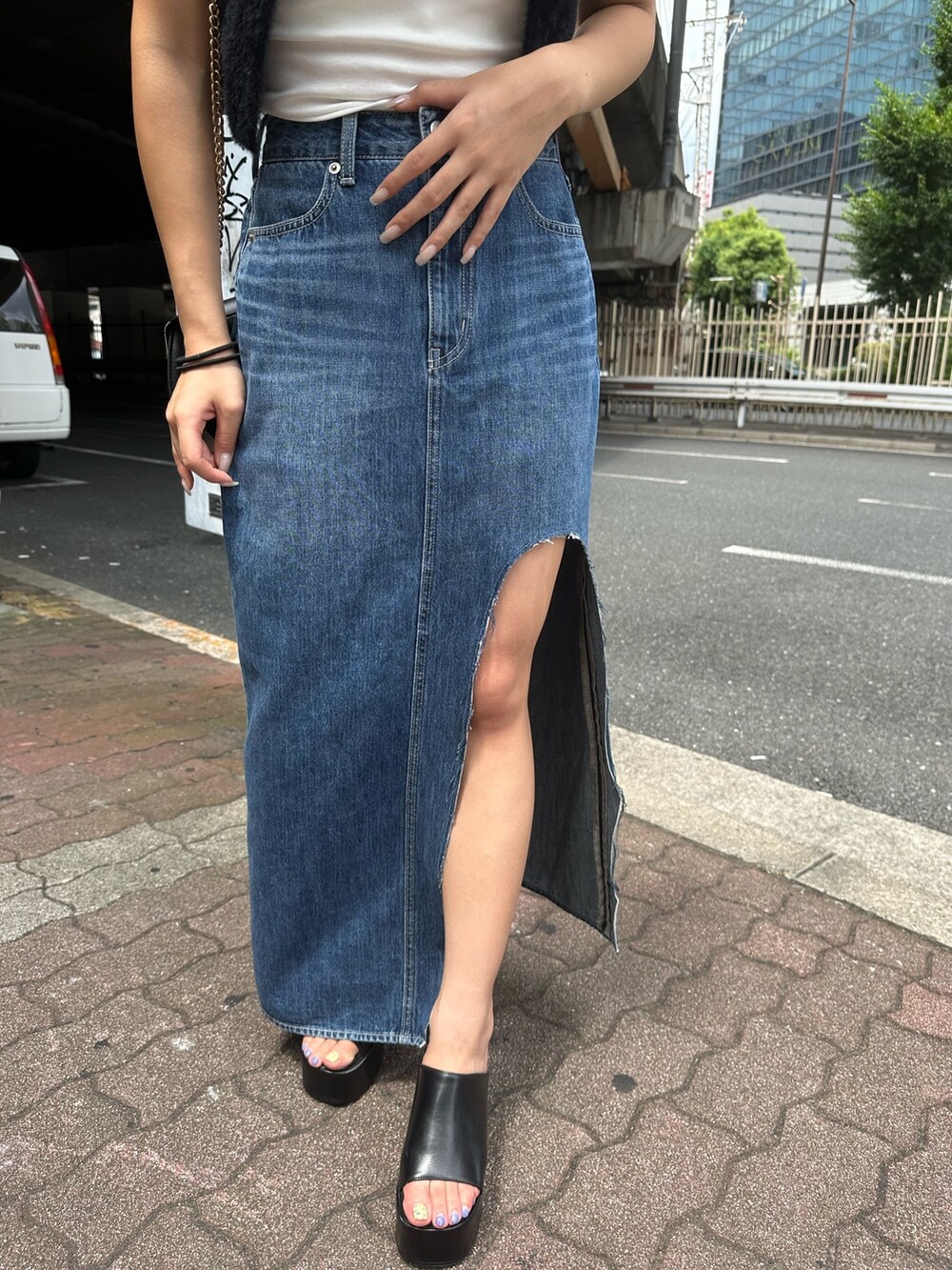 ブルー系のデニムスカート、ブラック系のサンダル、ブラック系のニット/セーターを着用したレディースの夏コーディネートの6枚目の写真