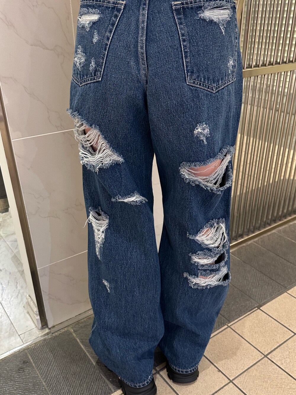 ブルー系のデニムパンツ、ブラック系のサンダル、イエロー系のニット/セーターを着用したレディースの春コーディネートの6枚目の写真